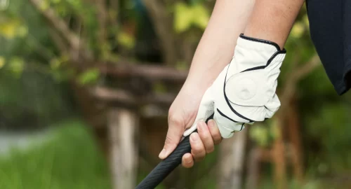 Close up on golfers hands holding a golf club, with a glove on one hand
