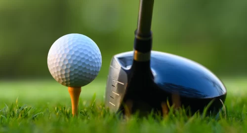 Golf ball on a tee with a club next to it