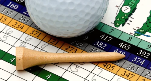 A close up of a golf score card with a tee and golf ball.