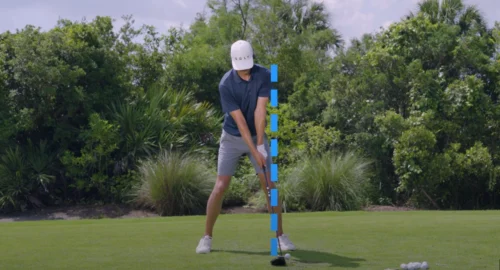Grant Horvat setting up the golf driver swing with a blue dotted line emphasizing then proper angle of his feet, shoulders and head.