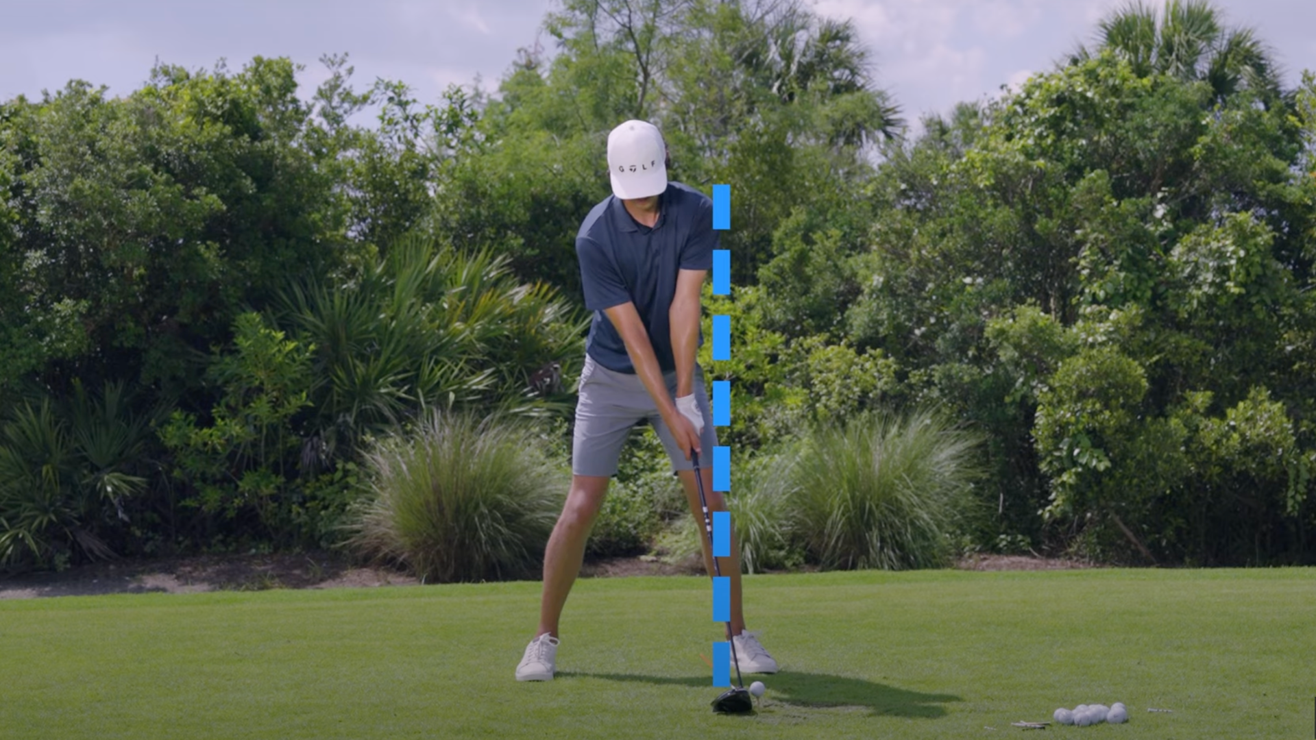 Grant Horvat setting up the golf driver swing with a blue dotted line emphasizing then proper angle of his feet, shoulders and head.