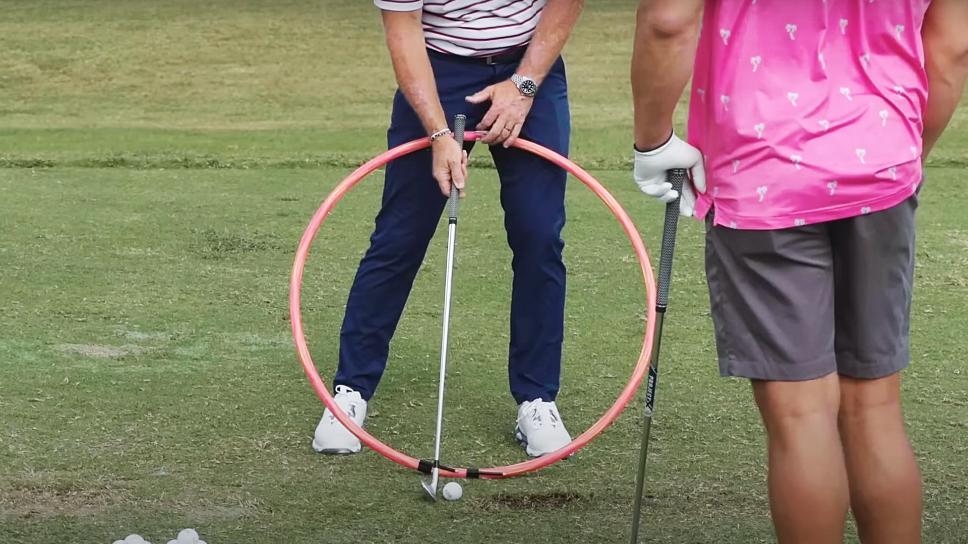 Golf coach Cameron McCormick holding a hula hoop as a visual aid with a golf club.