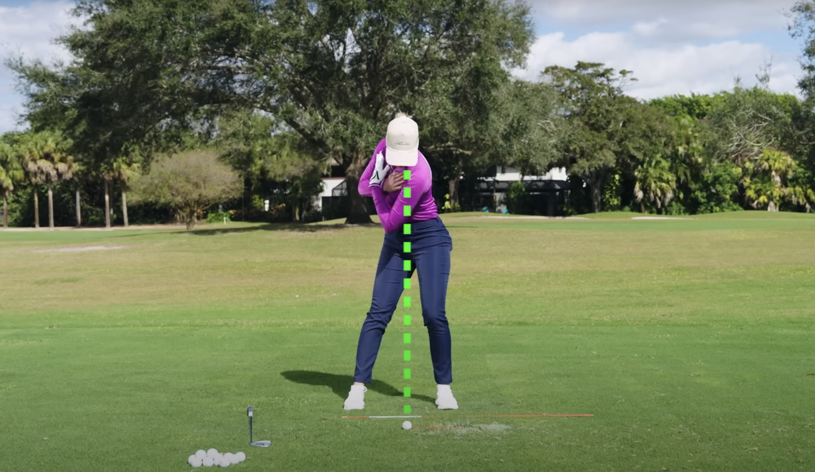 Performance Golf coach looking down at the ball with their arms crossed, showing the correct position of the body in relation to the ball position on the ground.