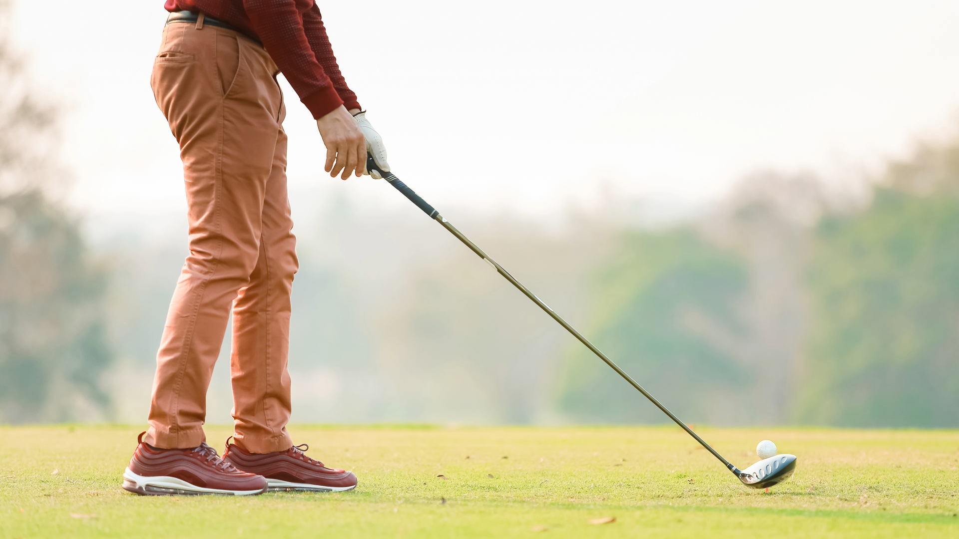 A man on the golf course wearing a long sleeve and pants on a chilly, foggy fall day.