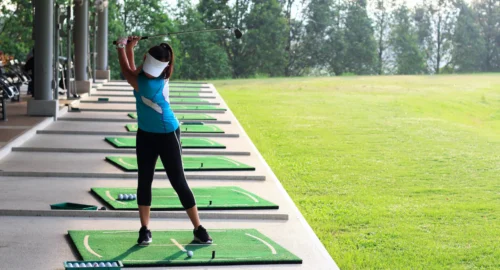 A woman practicing her golf swing at the driving range.