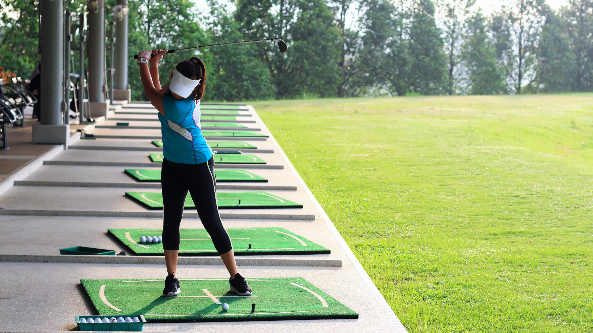 A woman practicing her golf swing at the driving range.