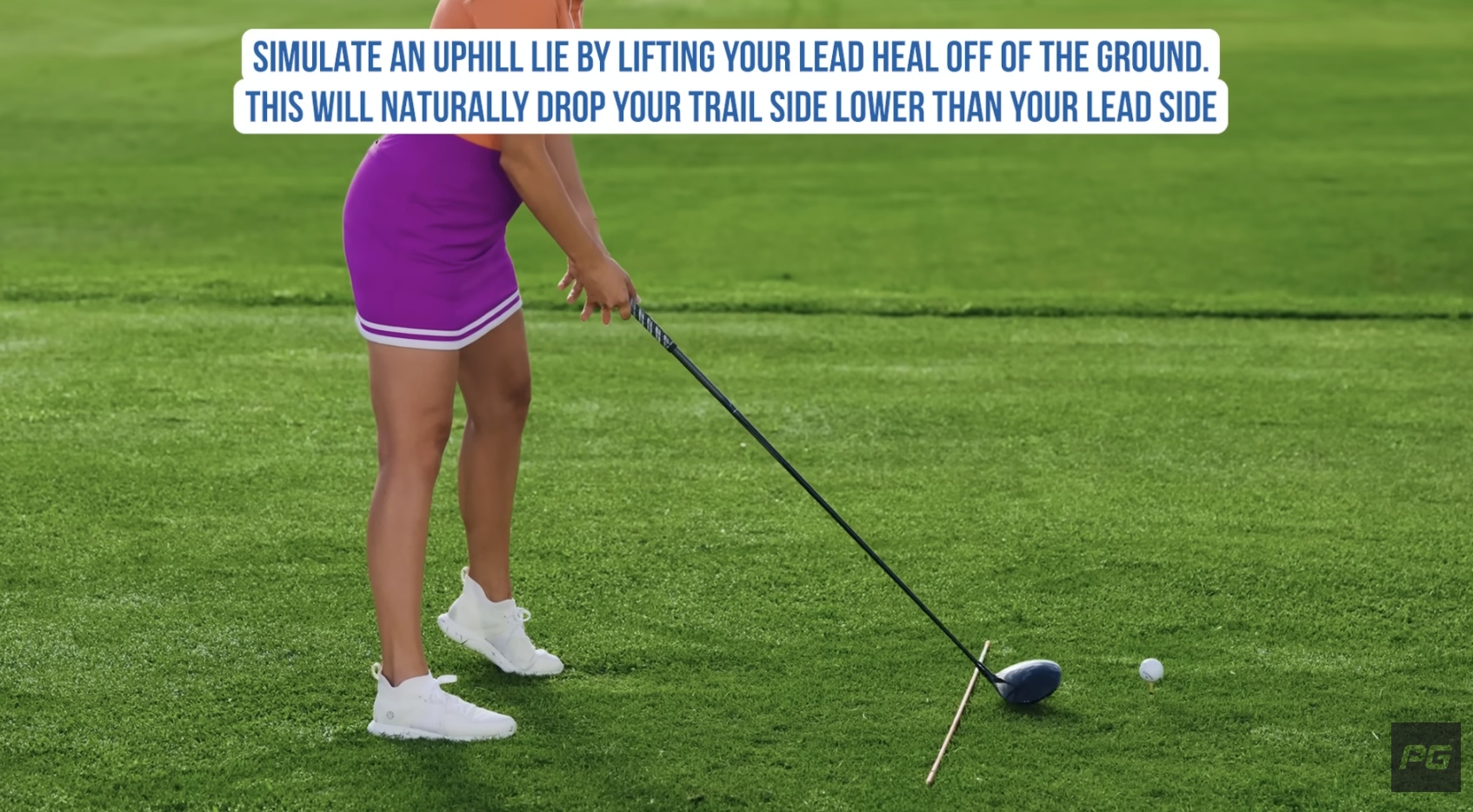 Performance Golf coach emulating an uphill lie by lifting their lead heal off the ground, encouraging the right hip tilt.